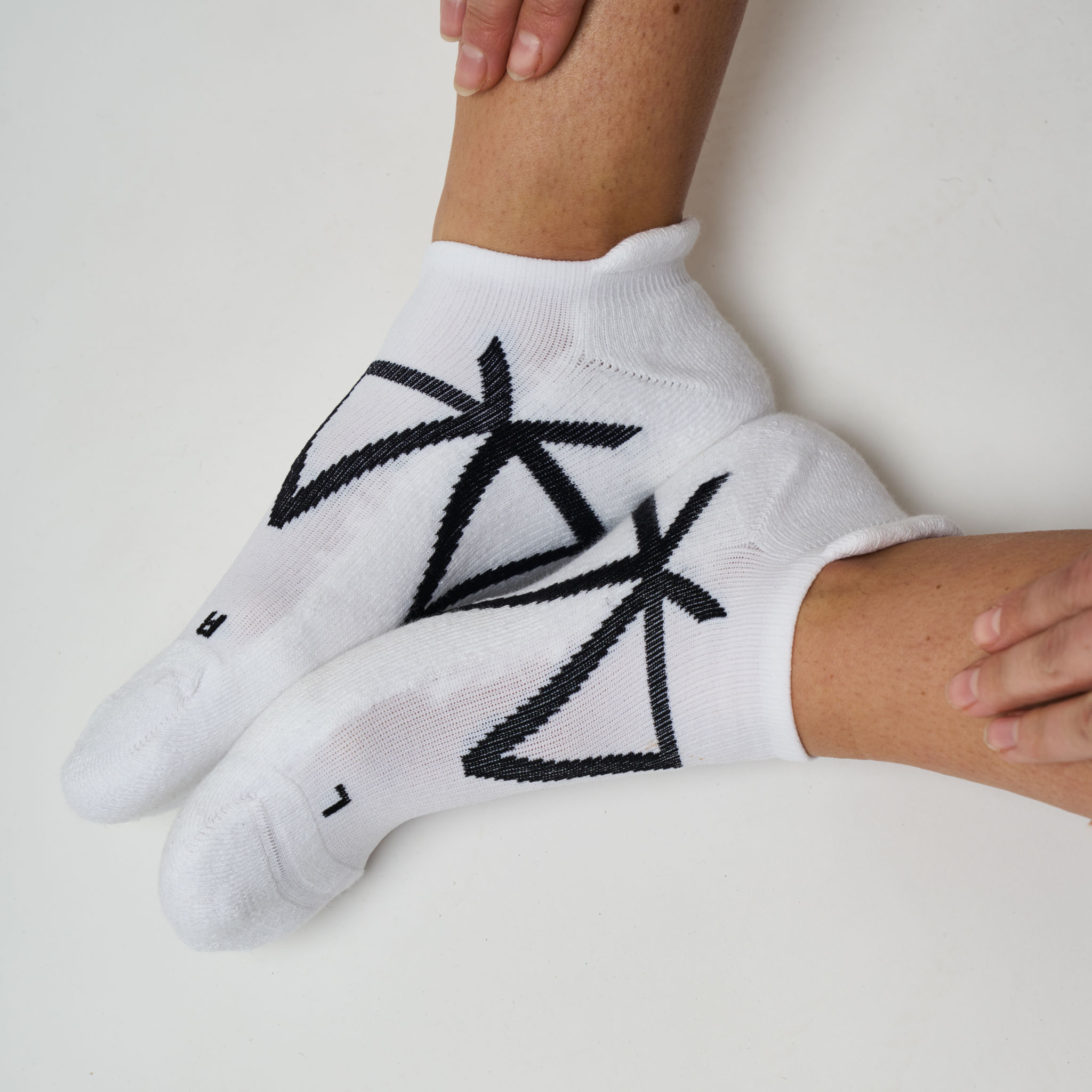 White socks with black MAAREE logo worn by a person on a light background