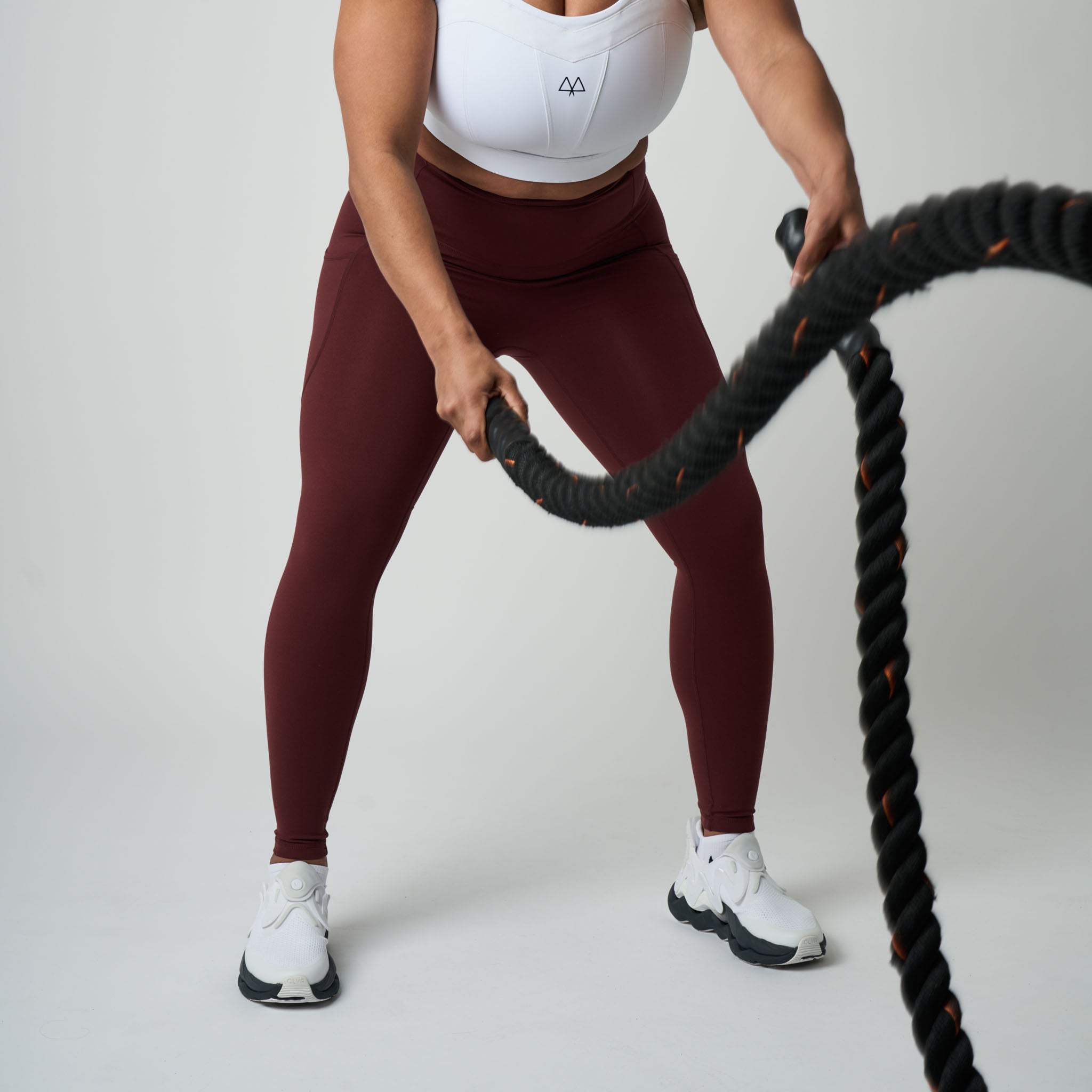 Person holding a battle rope against a plain background
