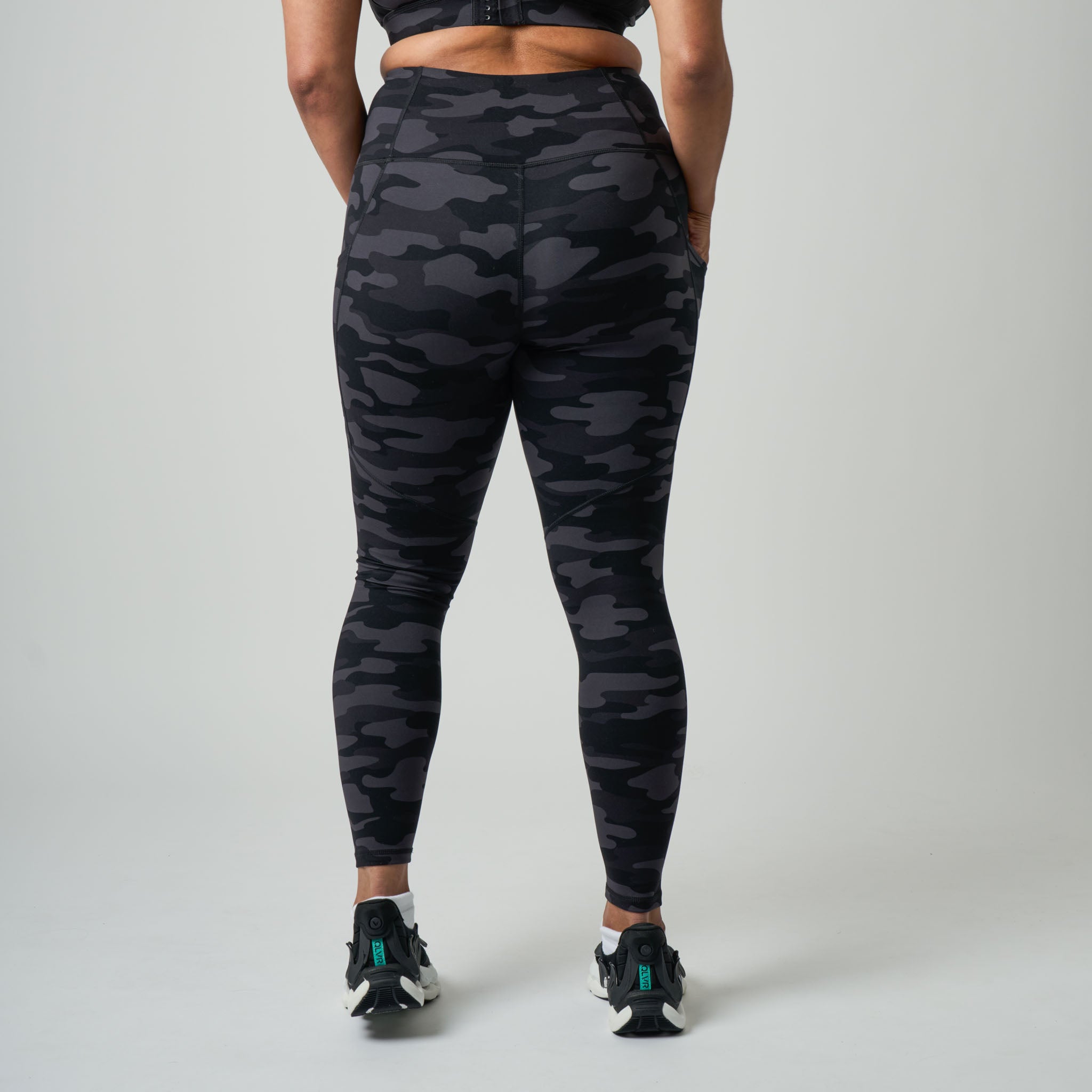 Person wearing black camouflage leggings on a gray background
