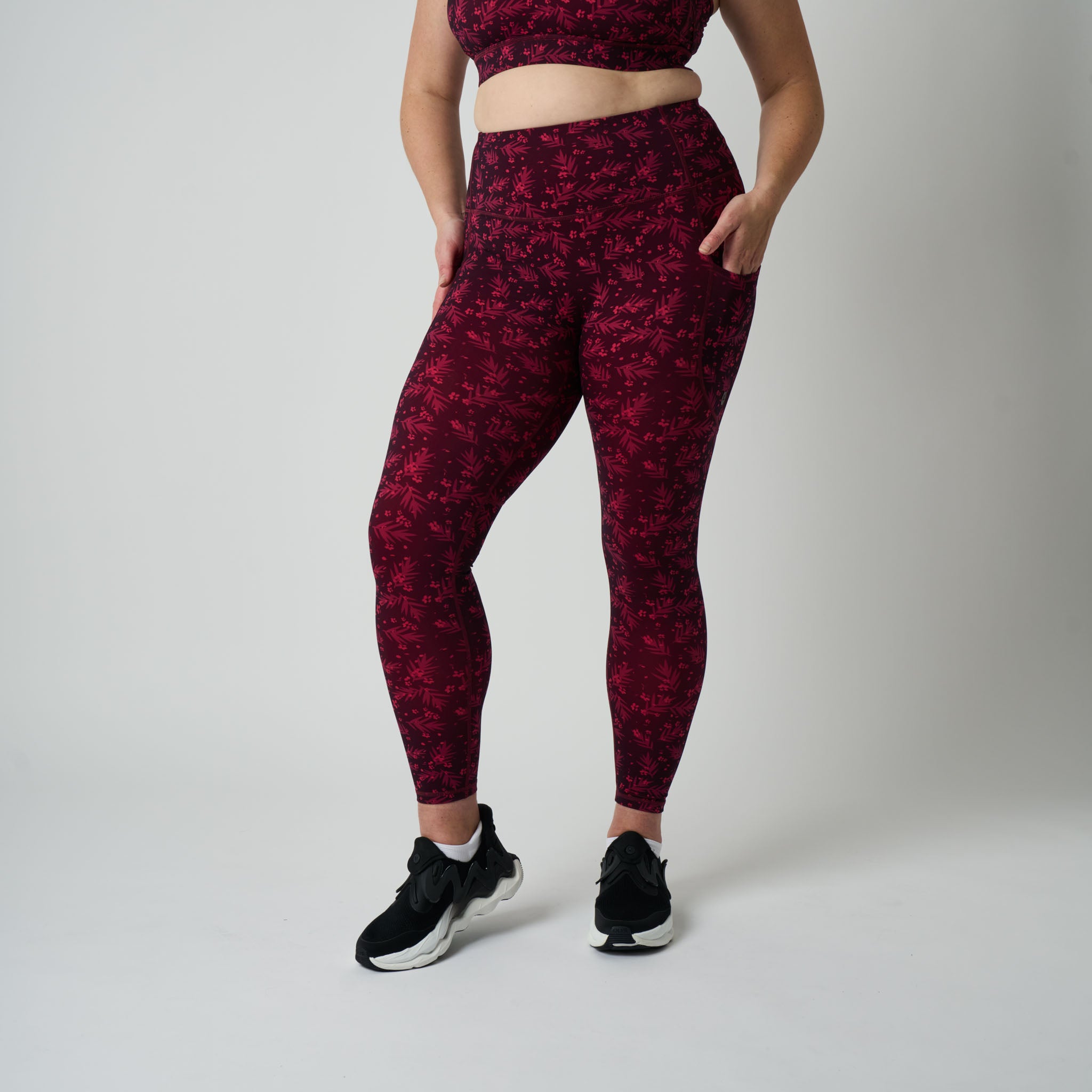 Person wearing maroon patterned leggings and sports bra on a plain background