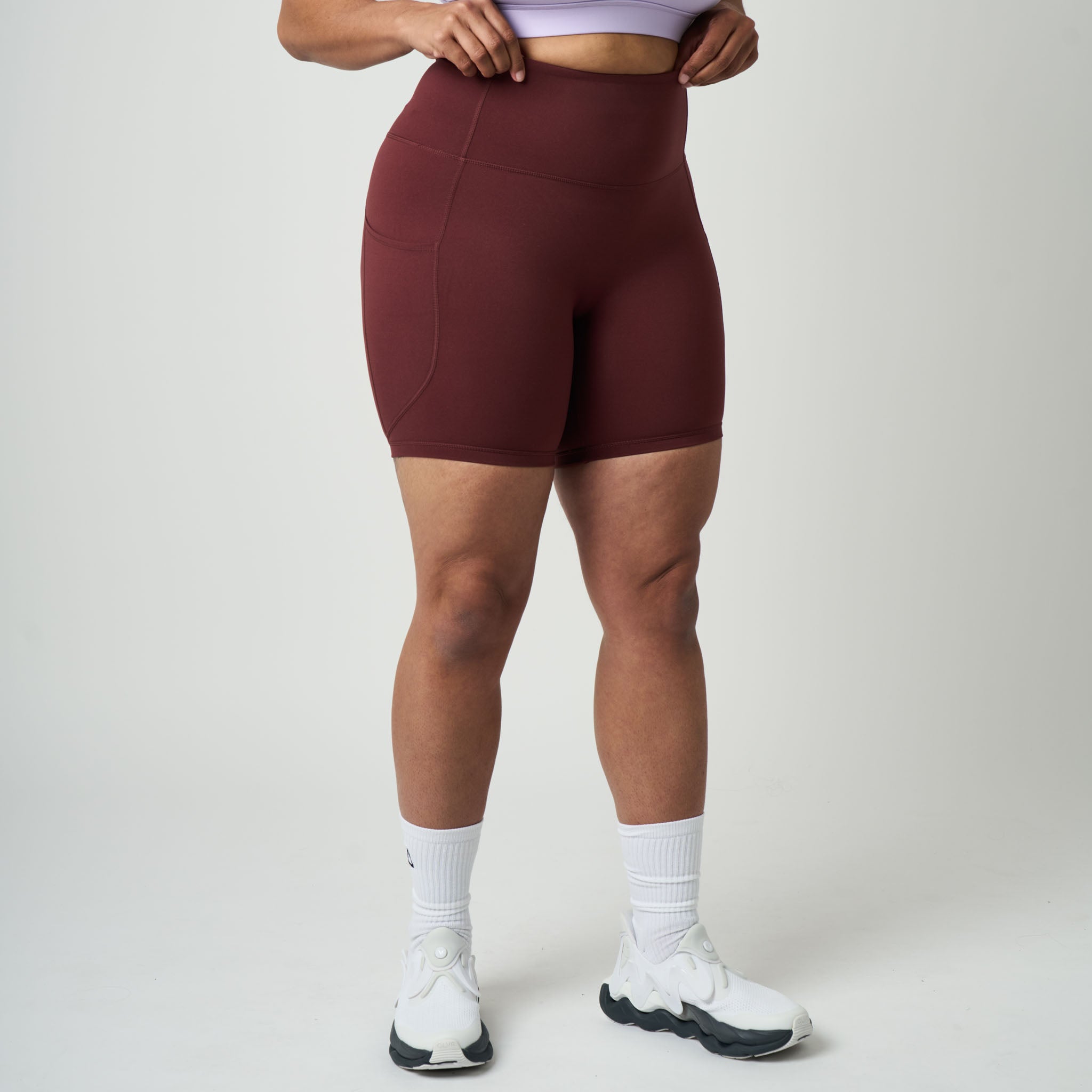 Person wearing maroon athletic shorts on a plain background