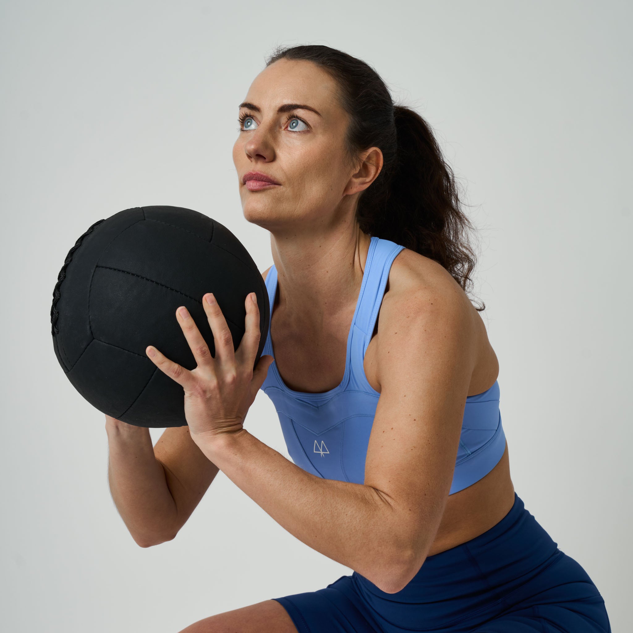 Woman holding a black medicine ball against a plain background