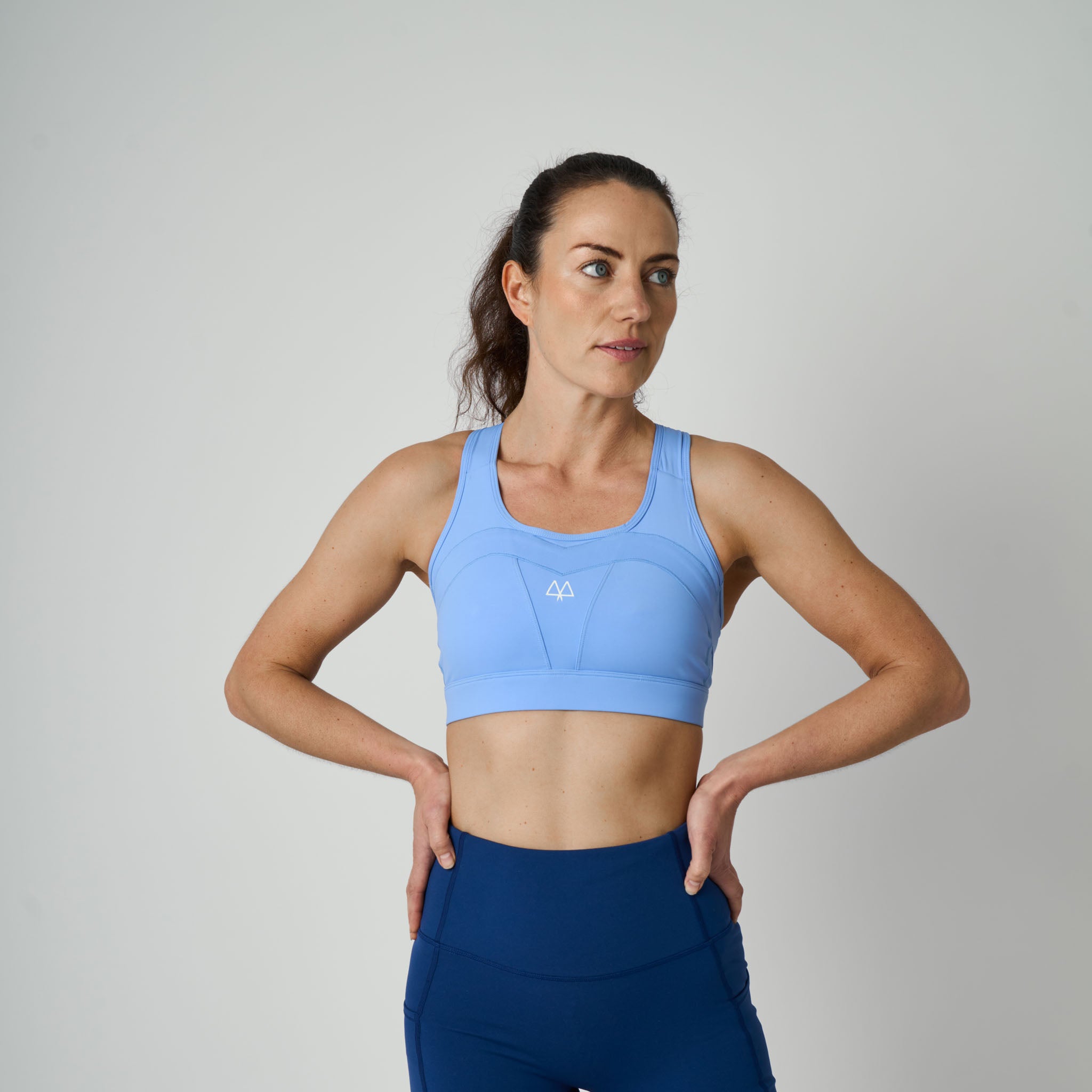 Woman wearing a blue sports bra and leggings on a gray background