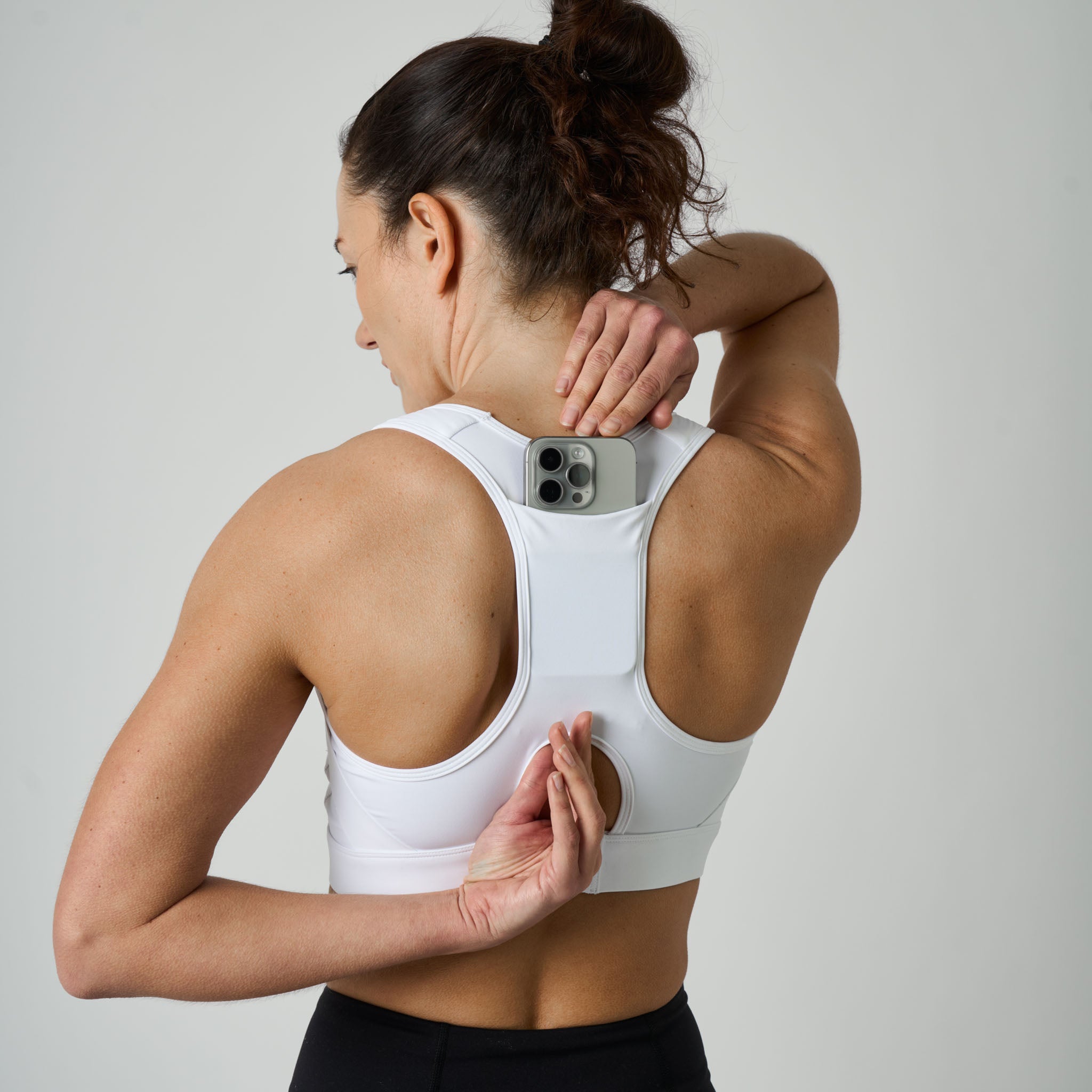 Woman wearing a white sports bra with a gray background
