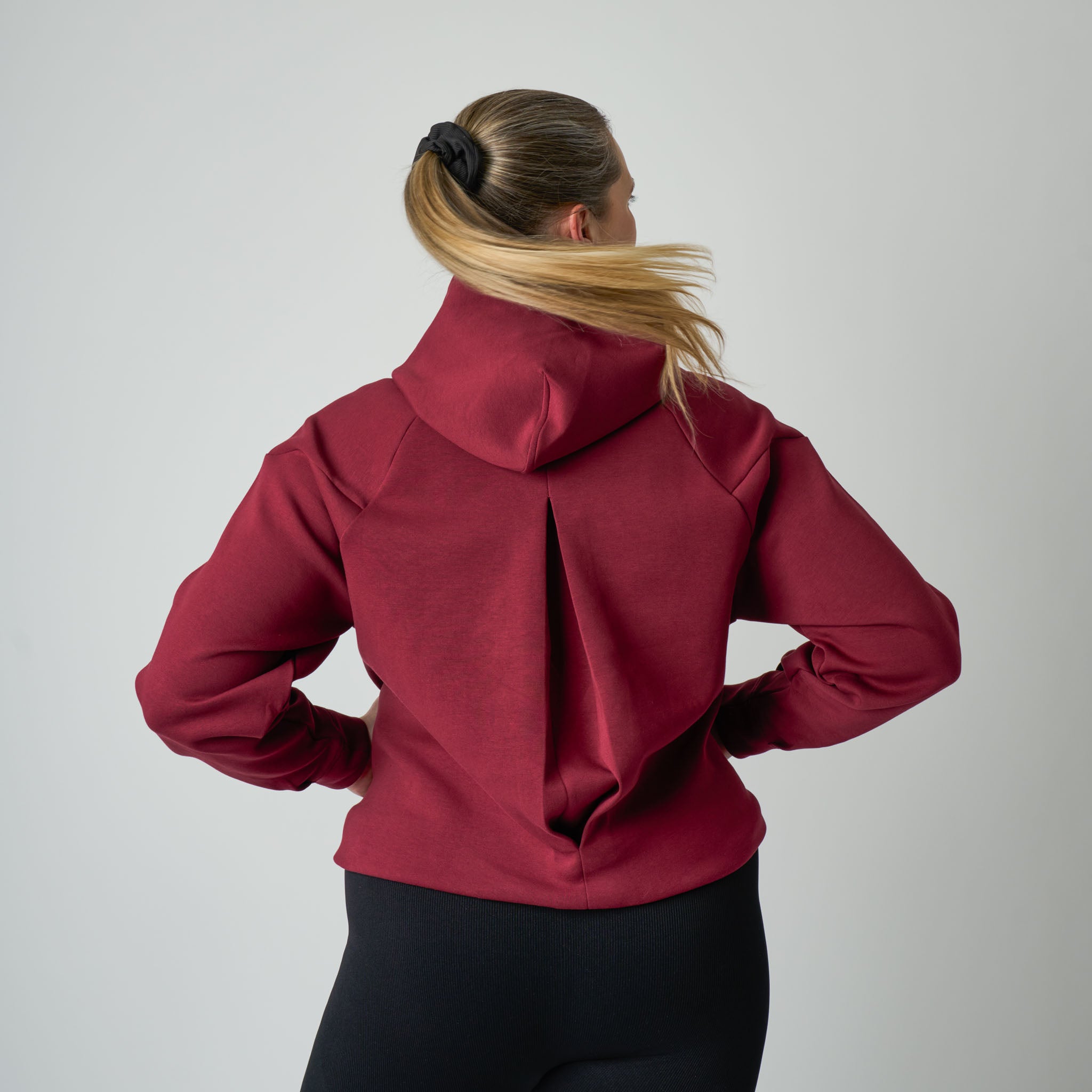 Person wearing a red hoodie from behind on a plain background