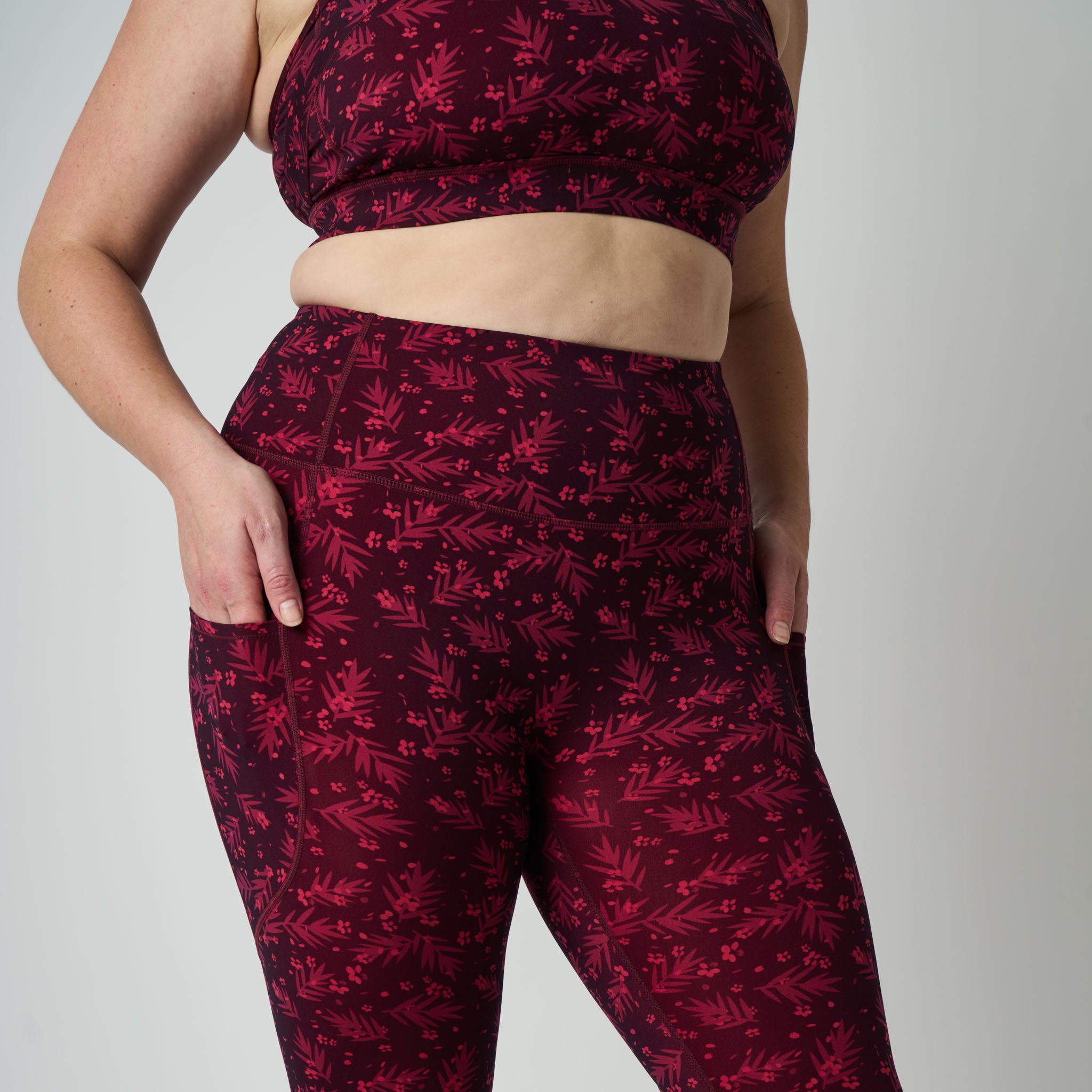 Person wearing a maroon sports bra and leggings with a floral pattern on a plain background