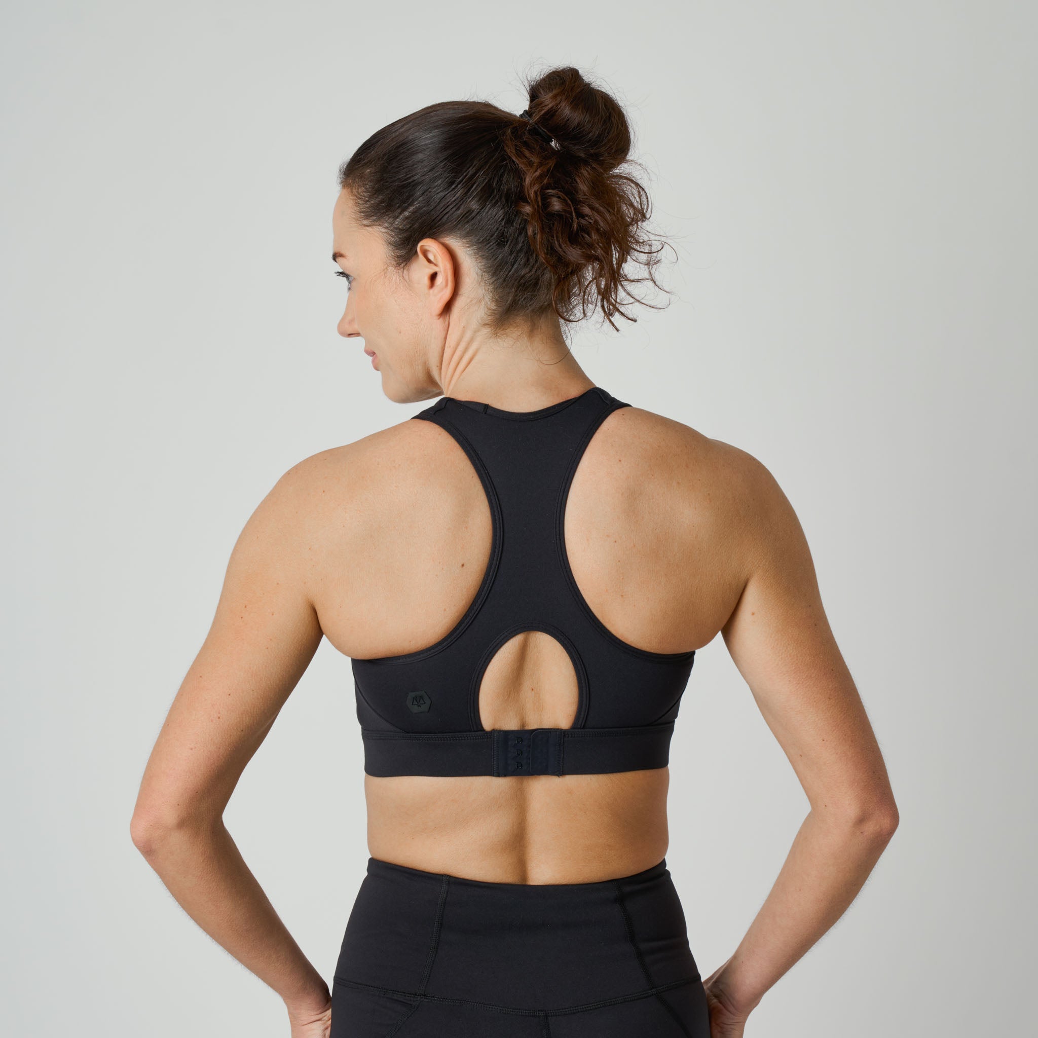 Woman wearing a black sports bra and leggings on a light gray background
