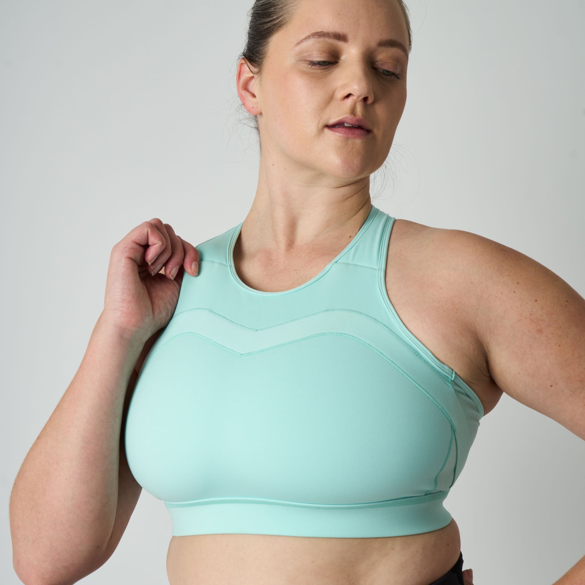 Woman wearing a light blue sports bra against a plain background