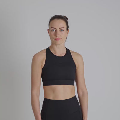 Woman wearing a black sports bra and shorts on a gray background